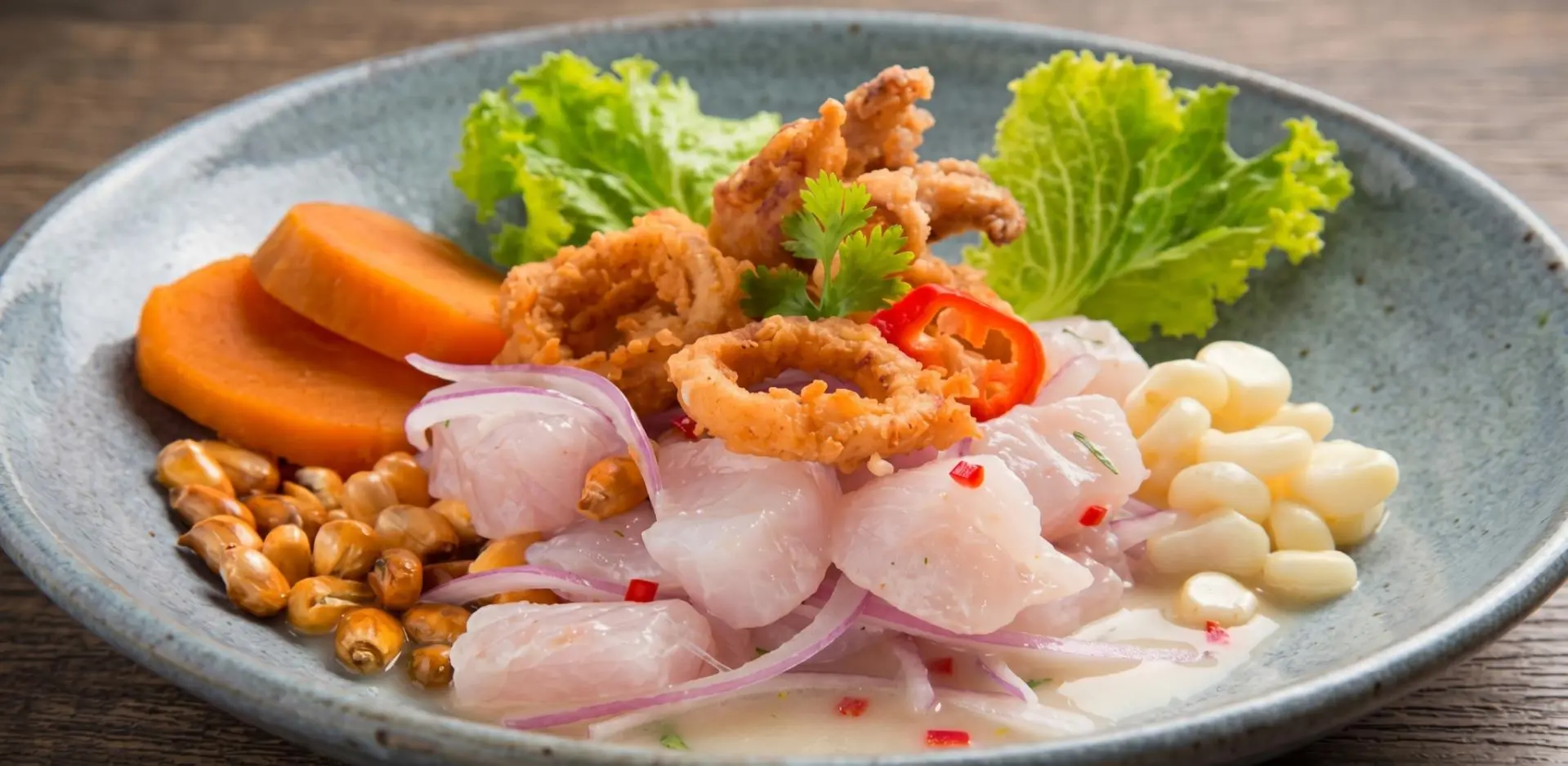 Plate of classic Peruvian ceviche with white fish, red onion, sweet potato, and choclo
