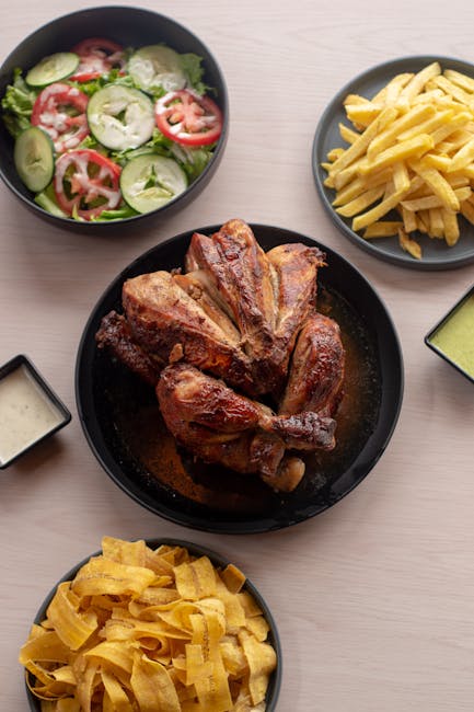 A quarter of pollo a la brasa with crispy mahogany skin, a mound of crinkle-cut fries, fresh lettuce salad, and three sauce ramekins (yellow ají, green huacatay, mayo) on a wooden table